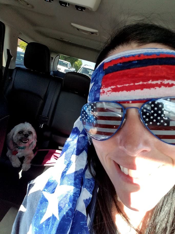Momma in a flag headband and star-spangled sunglasses with Paris grinning in the back seat on the Fourth of July.