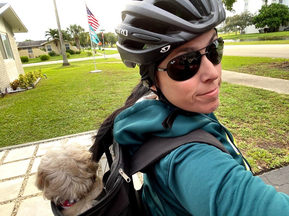 Momma in a bike helmet and sunglasses with Paris riding in the backpack carrier on her back