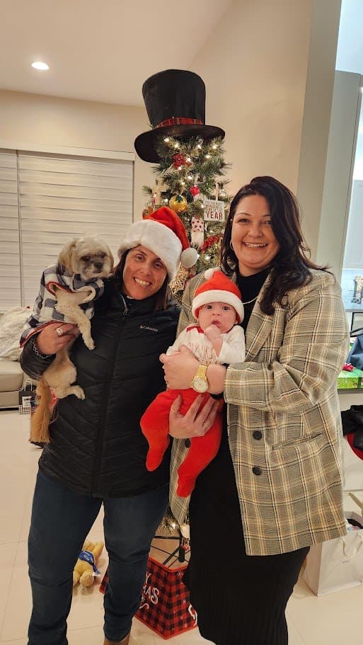Momma holding Paris by the Christmas tree next to her best friend and the newest little addition to the family